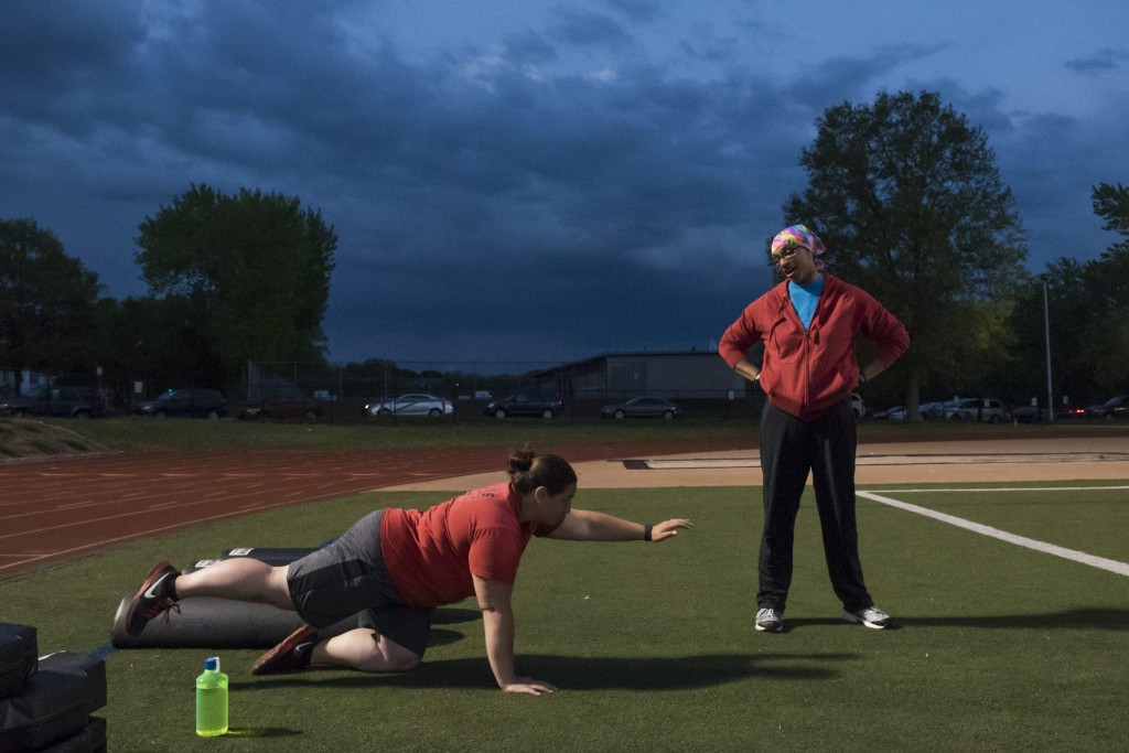 Boston Renegades Amanda Alpert (left) does core exercises to help her lower back as she talks to Torrance Brown (left), who is resting a hamstring injury on the sidelines during a practice at Dilboy Stadium on May 12, 2015. (Wicked Local Staff Photo/ Sam Goresh)
